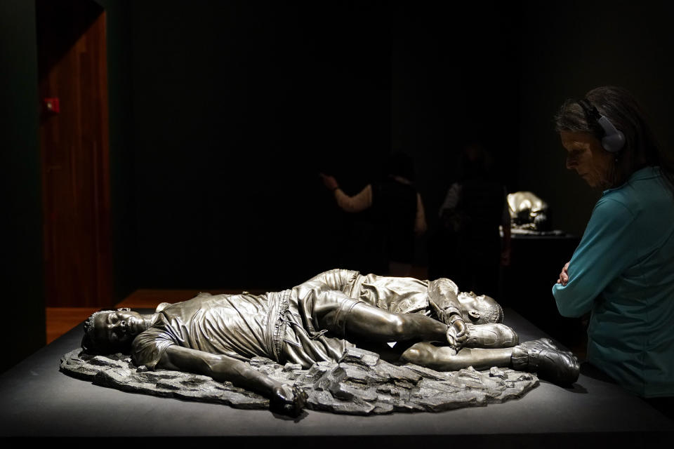 A woman looks at a bronze sculpture by Kehinde Wiley titled "Death of Two Soldiers," at the de Young Museum in San Francisco, Friday, March 24, 2023. The sculpture is part of the "Kehinde Wiley: An Archaeology of Silence," exhibition. (AP Photo/Godofredo A. Vásquez)