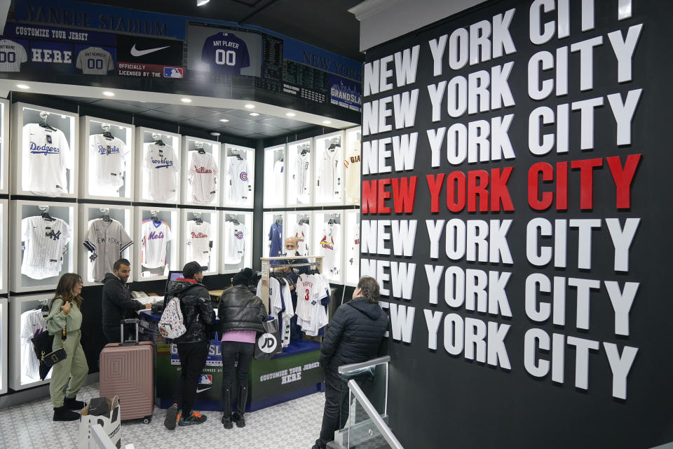 People shop at Grand Slam, a souvenir and sports apparel store, in Times Square, Monday, Nov. 15, 2021, in New York. Even as visitors again crowd below the jumbo screens in New York’s Times Square, the souvenir shops, restaurants, hotels and entrepreneurs within the iconic U.S. landmark are still reeling from a staggering pandemic. (AP Photo/Seth Wenig)