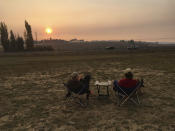 <p>Evacuees Ron Vitt, 75, left, and Ellen Brantley, 65, enjoy an evening at Sonoma Raceway sipping wine as smoke from several wildfires fills the sky Friday, Oct. 13, 2017, in Sonoma, Calif. They celebrated their 29th anniversary Sunday, Oct. 8. Their home is okay, so far. (Photo: Janie Har/AP) </p>