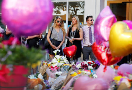 People look upon the flowers, messages and tokens left in tribute to the victims of the attact on Manchester Arena, in central Manchester, Britain May 26, 2017. REUTERS/Stefan Wermuth