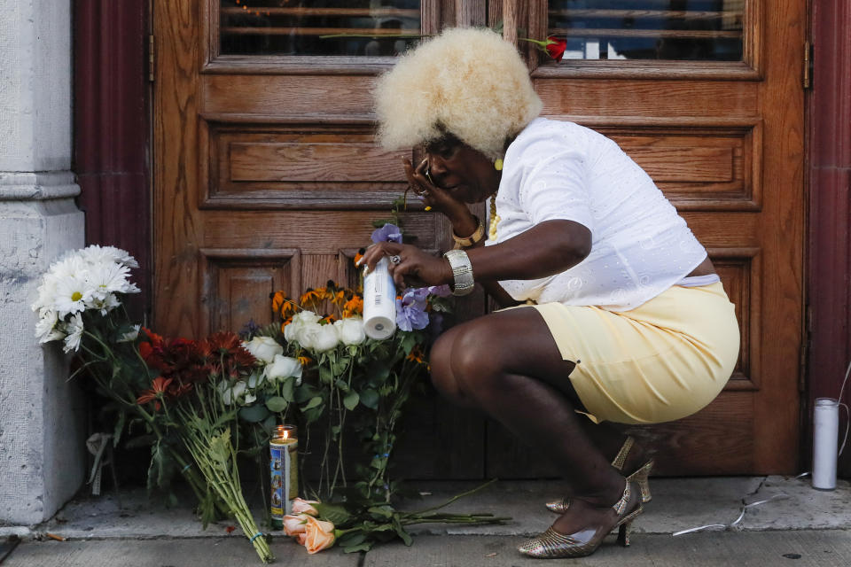 In this Aug. 4, 2019 photo Annette Gibson Strong places candles at a makeshift memorial for the slain and wounded at the scene of a mass shooting in Dayton, Ohio. Annette Gibson Strong started placing candles at a makeshift memorial the day of the shooting on Sunday. Strong says she’s continued to care for the memorial near Ned Peppers Bar in Dayton. It was outside the bar that Dayton police shot and killed the shooter as he approached the bar’s entrance. (AP Photo/John Minchillo)