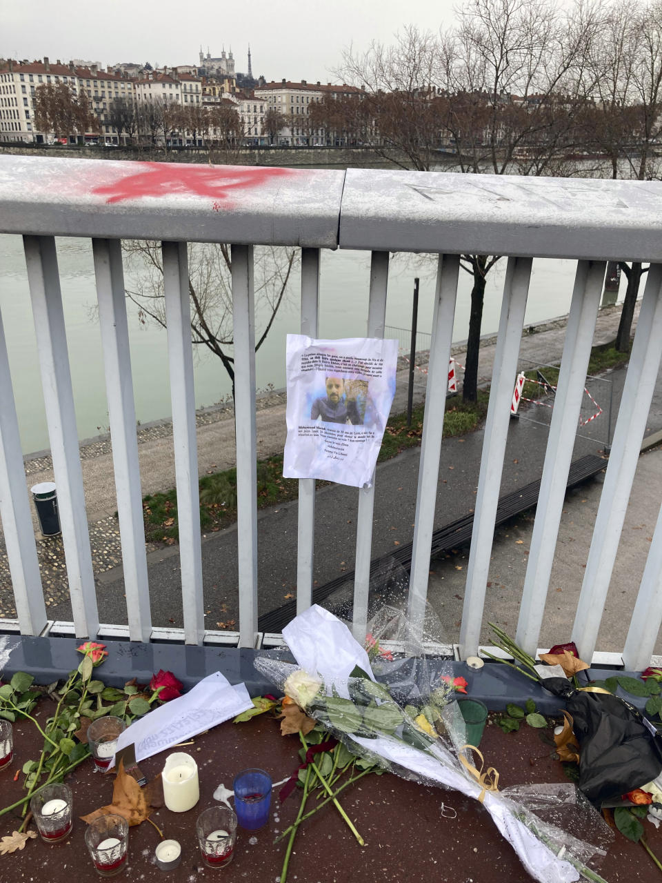 Flowers and candles are displayed in tribute of Mohammad Moradi, an Iranian activist who took his own life after jumping in the Rhone river in the French city of Lyon, Friday, Dec. 30, 2022. When a 38-year-old man anguished over the protests in Iran took his own life in the French city of Lyon, fellow members of the Iranian diaspora felt his pain. Three months into the anti-government protests that have swept Iran, Iranians abroad are going through a spectrum of emotions. (AP Photo/Nicolas Vaux-Montagny)