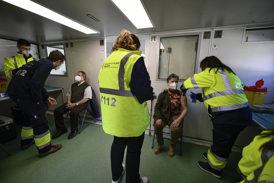 Lola Basaret, 57 and Julio Larrea, 88, are vaccinated with the Pfizer vaccine against coronavirus inside a mobile health unit in the small Pyrenees village of Oronoz-Mugaire, around 45 km (27 miles) from Pamplona, northern Spain, Tuesday, Jan. 19. 2021. (AP Photo/Alvaro Barrientos)