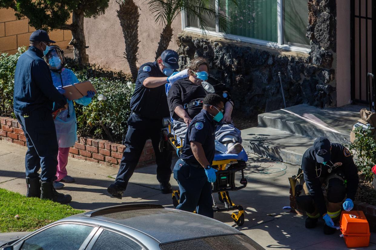 County of Los Angeles paramedics transport a potential COVID-19 patient after administering oxygen to him on the sidewalk in front of his building before taking him to a hospital on Jan. 21, 2021, in Hawthorne, Calif.