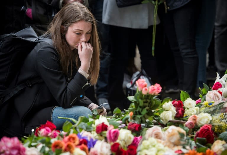 A woman reacts during a minute of silence to commemorate the victims of Friday's terror attack at a makeshift memorial near the site where a truck drove into Ahlens department store in Stockholm, Sweden, on April 10, 2017