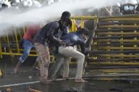 Students topple barricades as police fire tear gas and water cannons to disperse protesting members of the Inter University Students Federation during an anti government protest in Colombo, Sri Lanka, Thursday, May 19, 2022. Sri Lankans have been protesting for more than a month demanding the resignation of President Gotabaya Rajapaksa, holding him responsible for the country's worst economic crisis in recent memory. (AP Photo/Eranga Jayawardena)