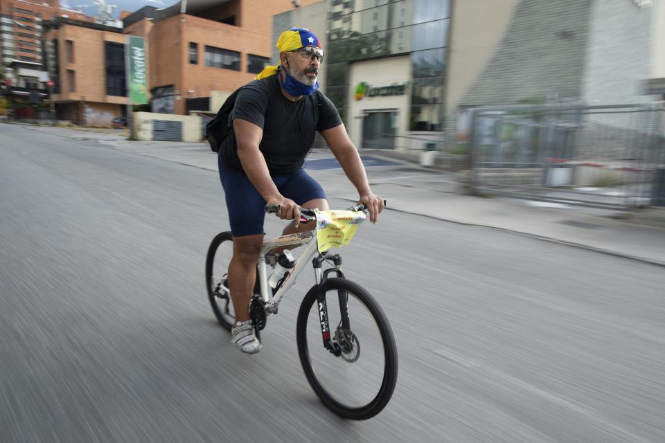 Andrés Burgos, un publicista de 55 años, monta su bicicleta con una mochila llena de arepas o empanadas de harina de maíz, en Caracas, Venezuela, el miércoles 21 de octubre de 2020. (AP Foto/Ariana Cubillos)