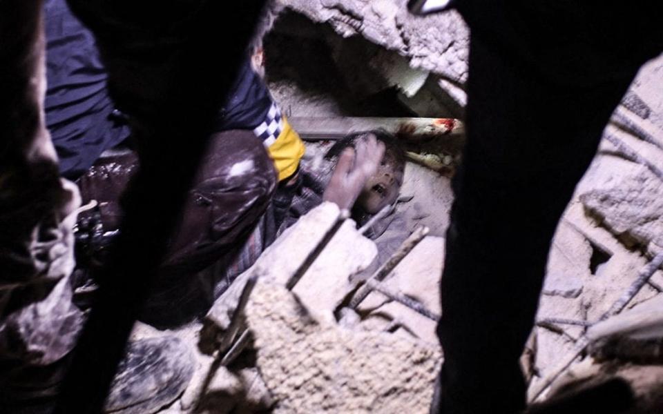 Rescuers try to free a young boy from the rubble of a collapsed building follwoing an earthquake, in the Syrian border town of Azaz - AFP