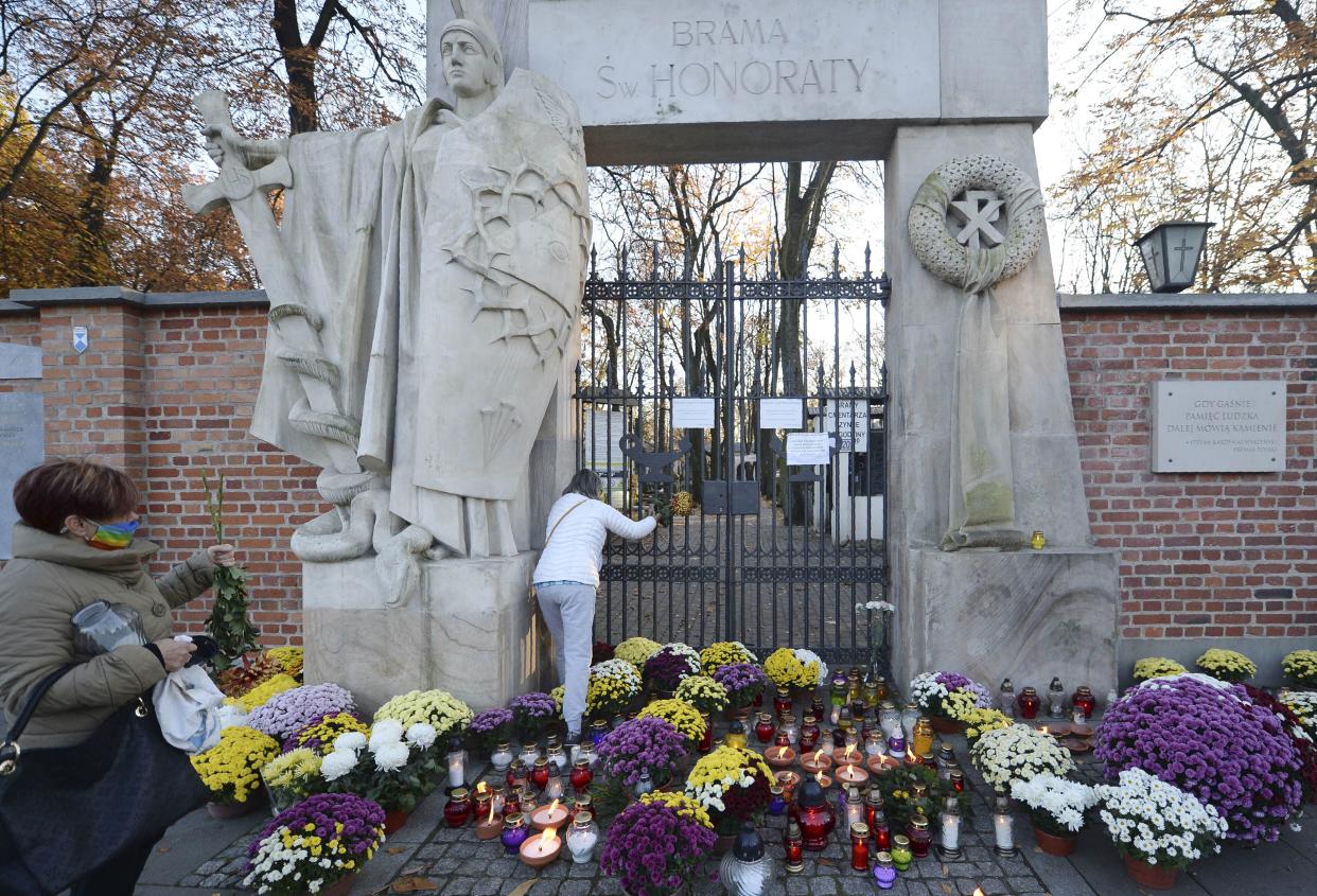 People left flowers and candles outside of Powazki cemetery after Poland's government closed all cemeteries in an attempt to curb the spread of COVID-19, in Warsaw, Poland on Sunday, Nov. 1, 2020. Driven by new solidarity, Poles have been buying armloads of chrysanthemums to help out flower vendors who unexpectedly faced bankruptcy when the government ordered all cemeteries locked due to COVID-19 during a traditional memorial weekend.