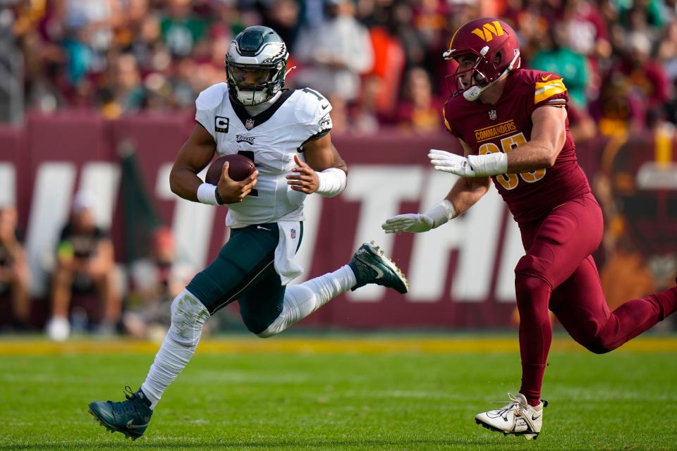 Philadelphia Eagles quarterback Jalen Hurts (1) is chased out of bounds by Washington Commanders defensive end Casey Toohill (95) during the second half of an NFL football game, Sunday, Oct. 29, 2023, in Landover, Md.