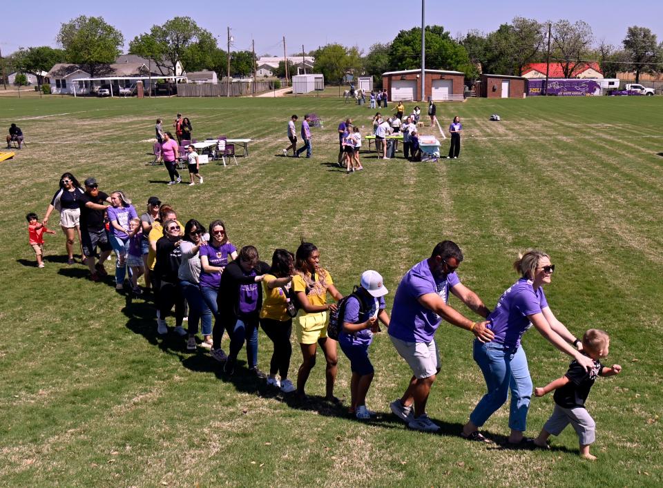 Children, parents and volunteers do a train dance as a DJ plays music at the Hardin-Simmons University Intramural Fields Saturday.