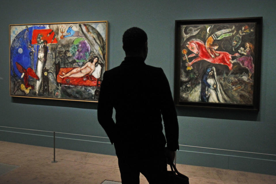 A member of the media views a painting by Russian artist Marc Chagall before the opening of the exhibition: Chagall, between War and Peace, at the Luxembourg museum in Paris, Tuesday Feb. 19, 2013. The exhibition starts February 21 and ends July 21, 2013. Painting at right is: 1944, Le Cheval Rouge, and at left: 1944, A Ma Femme.(AP Photo/Remy de la Mauviniere)