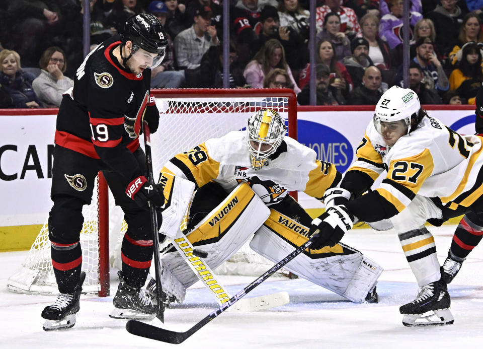 Pittsburgh Penguins goaltender Alex Nedeljkovic (39) watches as defenseman Ryan Graves (27) tries to move a rebound away from Ottawa Senators right wing Drake Batherson (19) during the second period of an NHL hockey game in Ottawa, Ontario, on Saturday, Dec. 23, 2023. (Justin Tang/The Canadian Press via AP)