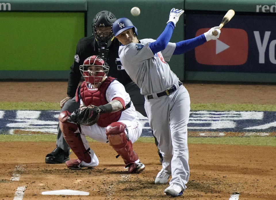 ARCHIVO - En esta foto del 24 de octubre de 2018, Manny Machado de los Dodgers de Los Ángeles Dodgers batea un sencillo frente al receptor Christian Vázquez de los Medias Rojas en el segundo juego de la Serie Mundial en Boston. (AP Foto/Elise Amendola, archivo)