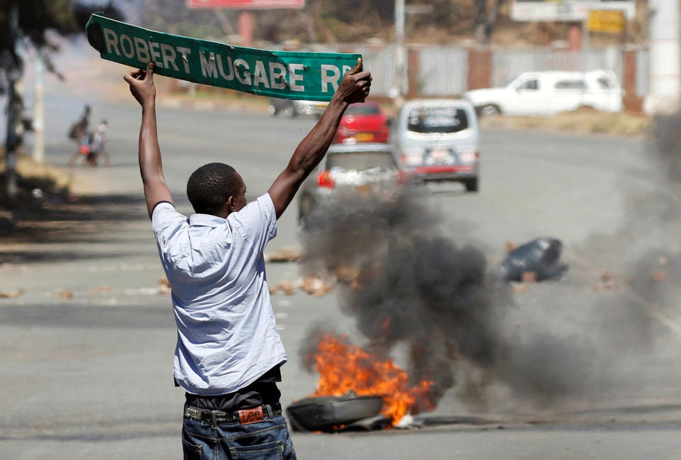 <p>A man carries a street sign as opposition party supporters clash with police in Harare, Zimbabwe, Aug. 26, 2016. (Photo: Philimon Bulawayo/Reuters) </p>