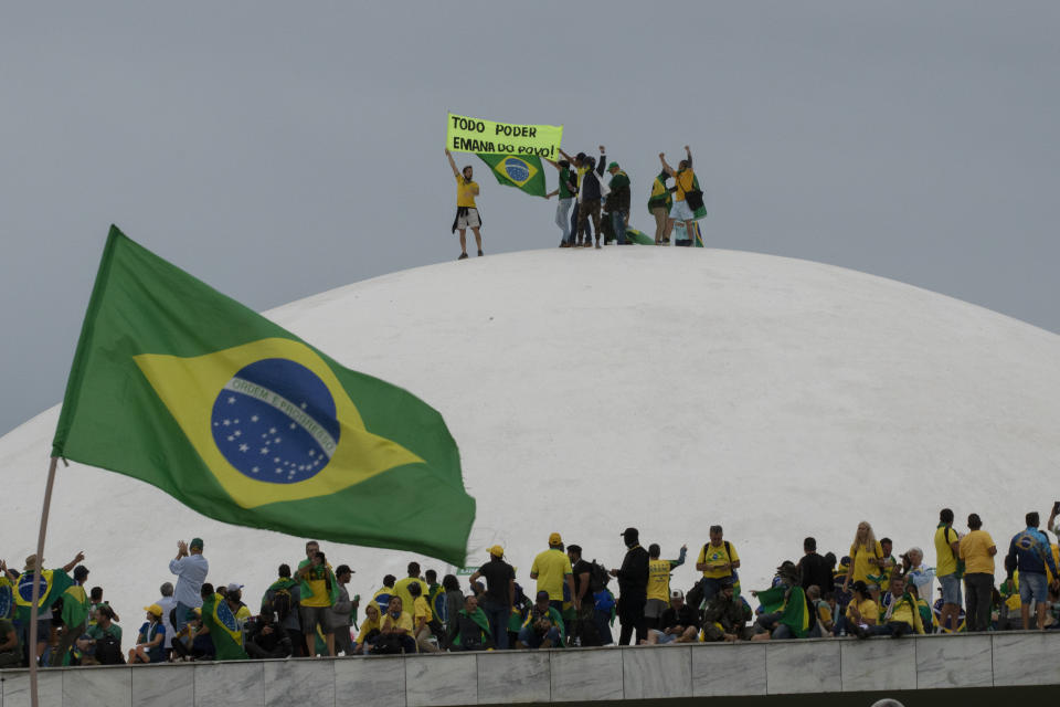 Supporters of former President Jair Bolsonaro  climb onto the roof of the National Congress, with a banner saying: All Power Comes From the People.