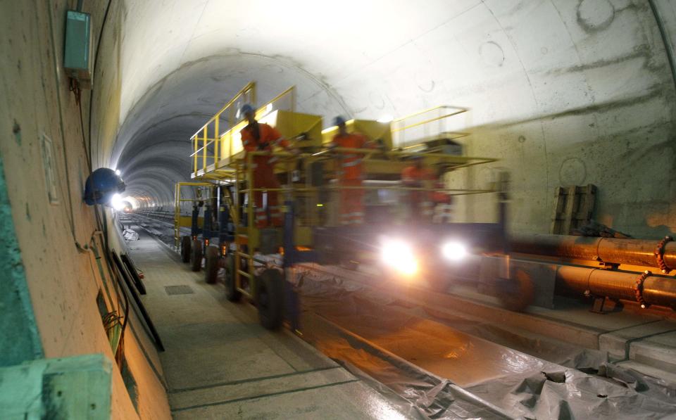 Workers drive on a special vehicle during the installation of the railway tracks in the NEAT Gotthard Base tunnel near Erstfeld