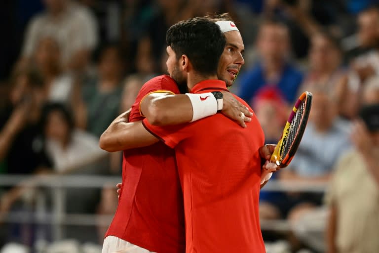 Rafael Nadal (D) y Carlos Alcaraz (I) se abrazan tras quedar eliminados en el torneo de dobles de París-2024, el 31 de julio de 2024 en Roland Garros (CARL DE SOUZA)