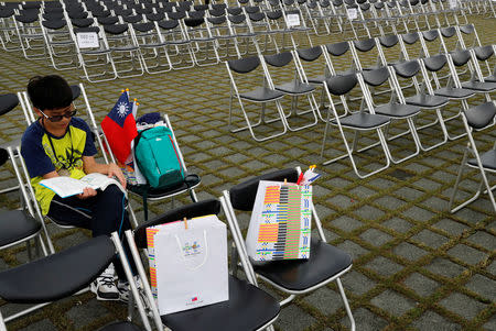 A boy reads as he sits next to a flag before the National Day celebrations in Taipei, Taiwan October 10, 2018. REUTERS/Tyrone Siu