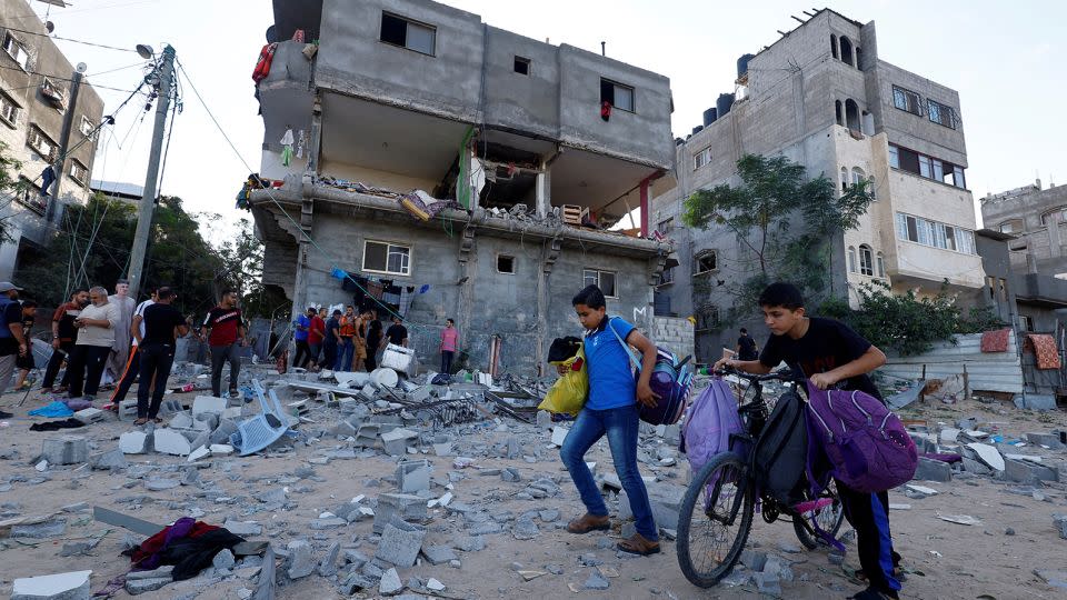 Young Palestinians walk in front of a damaged house in the aftermath of Israeli strikes in Khan Younis, Gaza, on October 30, 2023. - Mohammed Salem/Reuters