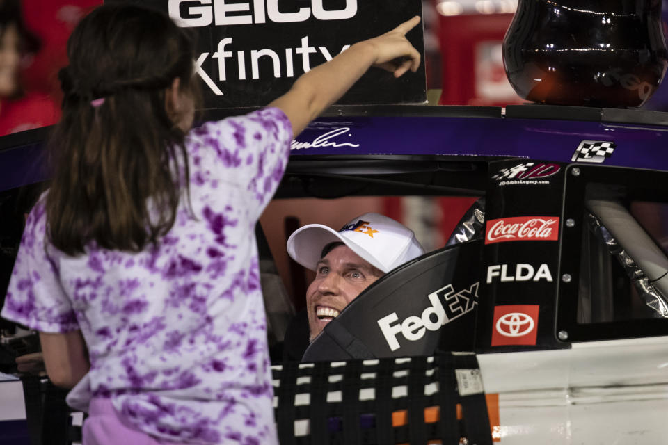 Denny Hamlin smiles in Victory Lane after being greeted by his daughter after winning a NASCAR Cup Series auto race at Charlotte Motor Speedway, Sunday, May 29, 2022, in Concord, N.C. (AP Photo/Matt Kelley)