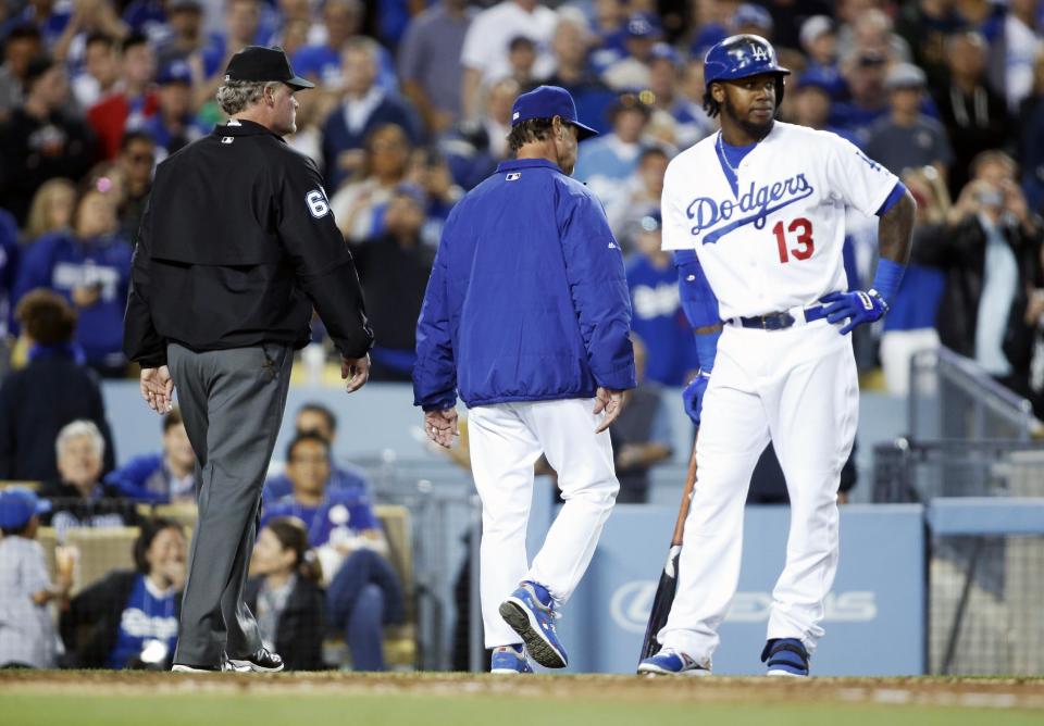 Los Angeles Dodgers' manager Don Mattingly leaves the field after being ejected as Hanley Ramirez, right, stands at the plate and umpire Ted Barrett, left, walks behind him against the San Francisco Giants during the seventh inning of a baseball game, Friday, May 9, 2014, in Los Angeles. (AP Photo/Danny Moloshok)