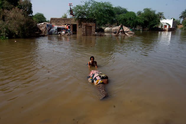 A man carries salvageable belongings from his flood-hit home in Shikarpur district of Sindh province on Aug. 31, 2022. (Photo: Fareed Khan/AP)