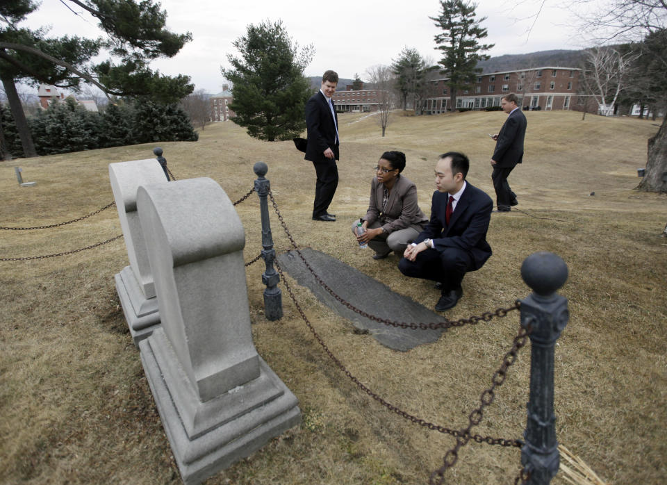 Tracy Davis, academic dean at Olivet University, and Christopher Chou, chief of staff at the World Evangelical Alliance, squat to read the tombstones of famed evangelist D.L. Moody and his wife on an historic 217-acre campus in Northfield, Mass., in this photo taken Thursday, March 8, 2012. The campus, along with its 43 buildings, is being offered for free to an orthodox Christian group who can come up a solid plan to use it. (AP Photo/Elise Amendola)