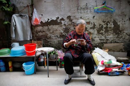 Migrant Mrs Zhong embroiders shoe inlays outside her one room home at the outskirts of Beijing, China October 1, 2017. REUTERS/Thomas Peter