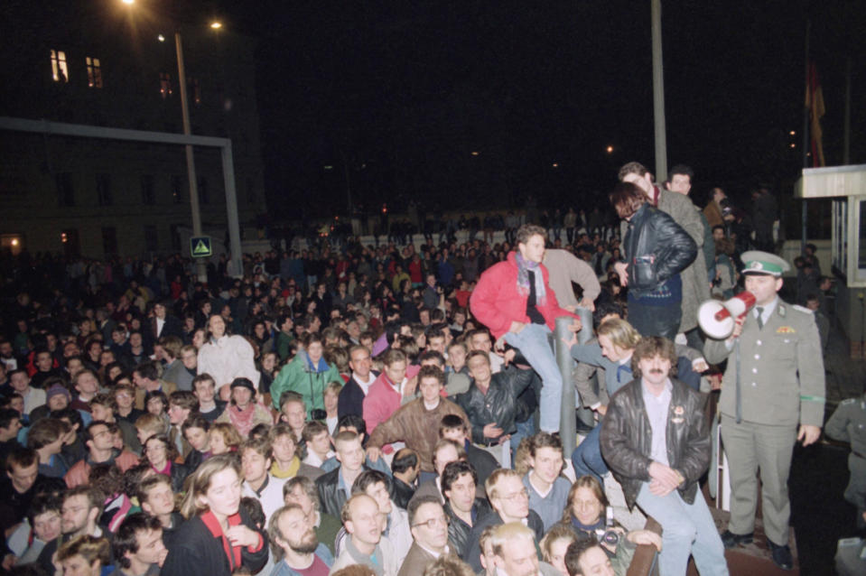 FILE - In this Friday Nov. 10, 1989 file photo, Berliners from East and West crowd the area in front of a border fence at this border crossing point in East Berlin watched by East German border police. The border gates opened following the announcement by the East German government. (AP Photo/Lutz Schmidt)