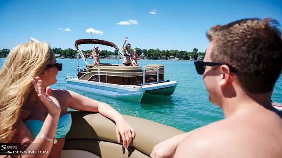 People waving to others on a pontoon boat