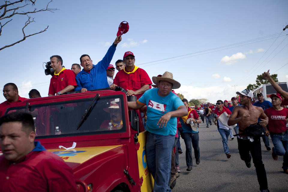 Venezuela's President Hugo Chavez waves to supporters from the of a vehicle driven by Venezuela's Foreign Minister Nicolas Maduro during a campaign caravan from Barinas to Caracas, in Sabaneta, Venezuela, Monday, Oct. 1, 2012. Venezuela's presidential election is scheduled for Oct. 7. (AP Photo/Rodrigo Abd)