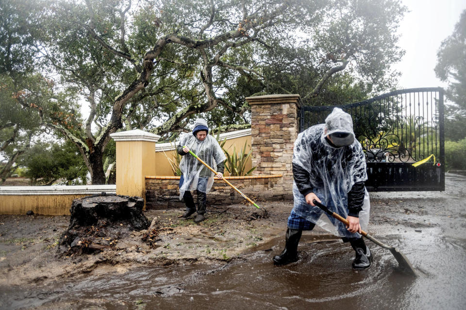 Alex, left, and Aron Moreno work to divert water from their property as heavy rains fall in Salinas, Calif., on Wednesday, Jan. 27, 2021. The couple lives below hillsides scorched in last year's River Fire where water and mud is now flowing downhill from burned land. lAP Photo/Noah Berger)