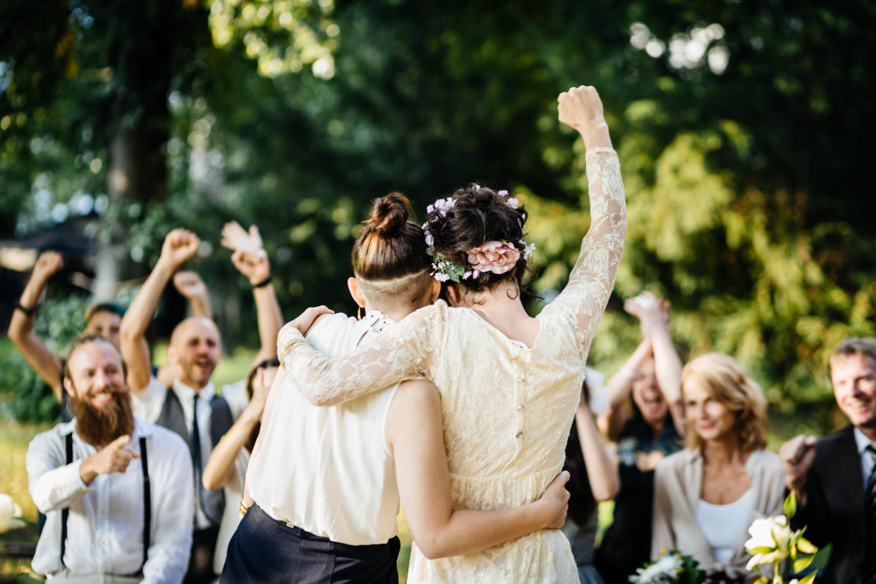 Young lesbian couple celebrating their marriage in front of their friends. The wedding ceremony is outdoors