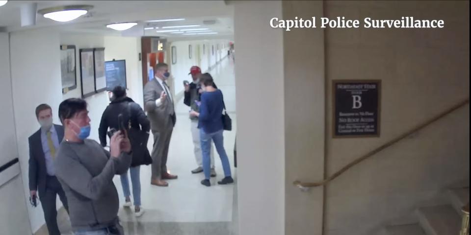 Tour attendee takes a photo of a stairwell in Longworth House Office Building as Rep. Loudermilk speaks to other tour attendees in the hallway.