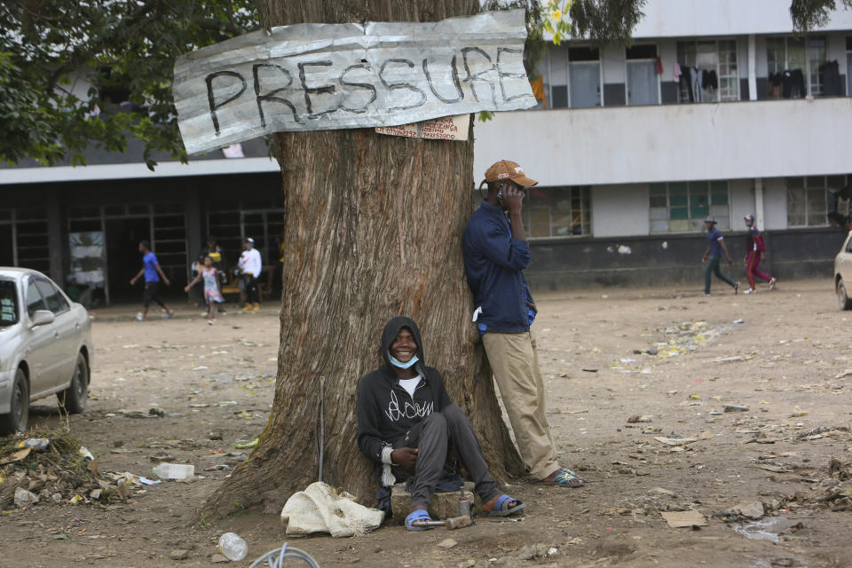 Two men relax under a tree in a poor township on the outskirts of the capital Harare, Tuesday, Nov, 16, 2021. When the coronavirus first emerged last year, health officials feared the pandemic would sweep across Africa, killing millions and destroying the continent’s fragile health systems. Although it’s still unclear what COVID-19’s ultimate toll will be, that catastrophic scenario has yet to materialize in Zimbabwe or much of Africa. (AP Photo/Tsvangirayi Mukwazhi)
