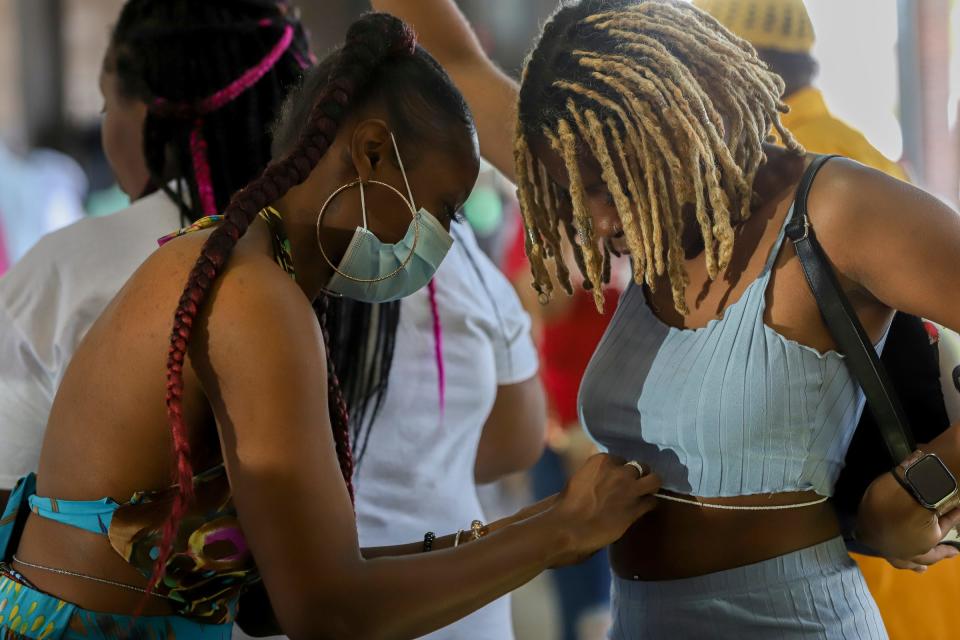 Micah Thomas, 31, of Detroit ties waist beads to Jalea Jones, 22, of Detroit at the Juneteenth Fest at the Eastern Market in Detroit on Sunday, June 19, 2022. 