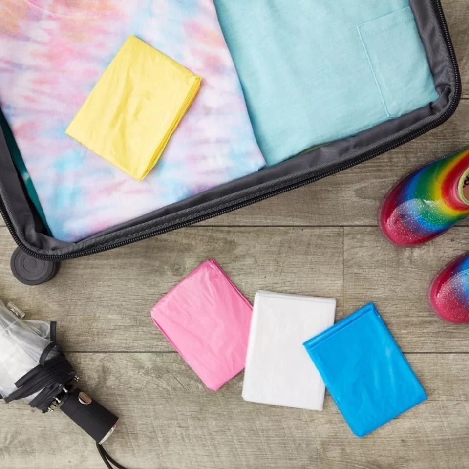 Open suitcase with neatly packed clothing, colorful shoes, and the rectangular, folded-up, multicolor ponchos