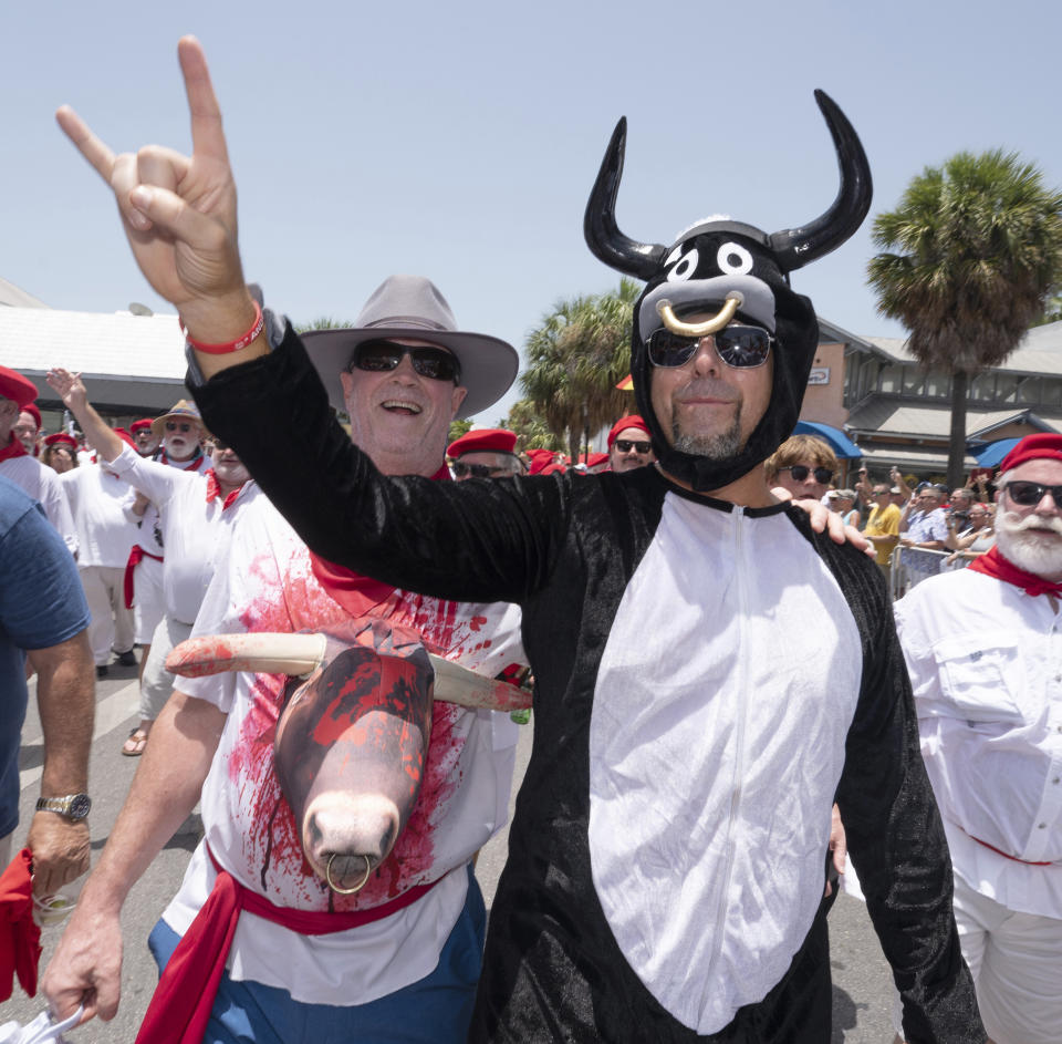 In this photo provided by the Florida Keys News Bureau, Hemingway Days festival attendees have fun with costuming as they join Ernest Hemingway look-alikes during the annual "Running of the Bulls" Saturday, July 22, 2023, in Key West, Fla. The lighthearted take-off on the famed run in Pamplona, Spain, features replica bulls on wheels and is a focal element of the island city's annual Hemingway Days festival that ends Sunday, July 23. The Nobel Prize–winning author lived and wrote in Key West throughout most of the 1930s. (Andy Newman/Florida Keys News Bureau via AP)