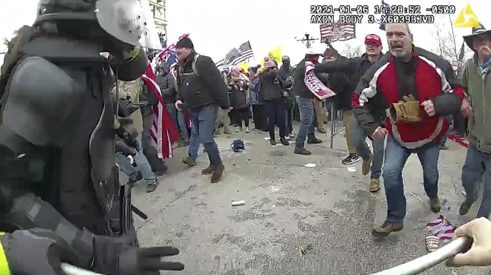 This still frame from Metropolitan Police Department body worn camera video shows Thomas Webster, in red jacket, at a barricade line at on the west front of the U.S. Capitol on Jan. 6, 2021, in Washington. Webster, a Marine Corps veteran and retired New York City Police Department Officer, is accused of assaulting an MPD officer with a flagpole. A number of law enforcement officers were assaulted while attempting to prevent rioters from entering the U.S. Capitol. (Metropolitan Police Department via AP)