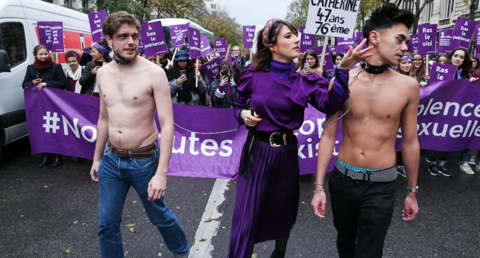 Two men wearing chains around their neck take part in march in Paris for violence against women.