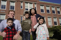 John Horrigan, top left, and his wife Kim Horrigan, top right, stand for a photograph with their children, from the left, William, 3, Conor, 8, and Sofia, 4, all of Quincy, Mass., outside Montclair Elementary School, in Quincy, Tuesday, April 13, 2021. Kim said she and her husband have struggled all year with their decision to keep their 8-year-old son in remote learning due to the coronavirus pandemic. (AP Photo/Steven Senne)