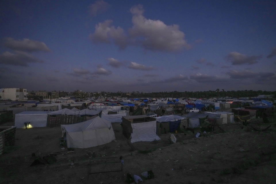 A Palestinian man, displaced by the Israeli air and ground offensive on the Gaza Strip, checks a makeshift tent during the dusk at a camp in Deir al Balah, Monday, May 13, 2024. Palestinians on Wednesday, May 15, 2024, will mark the 76th year of their mass expulsion from what is now Israel. It's an event that is at the core of their national struggle, but in many ways pales in comparison to the calamity now unfolding in Gaza. (AP Photo/Abdel Kareem Hana)