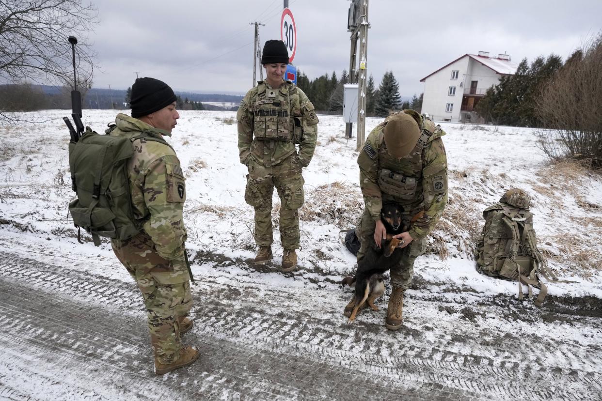 A U.S. soldier plays with a dog at a military camp in Arlamow, southeastern Poland, near the border with Ukraine, on Monday, Feb. 28, 2022.