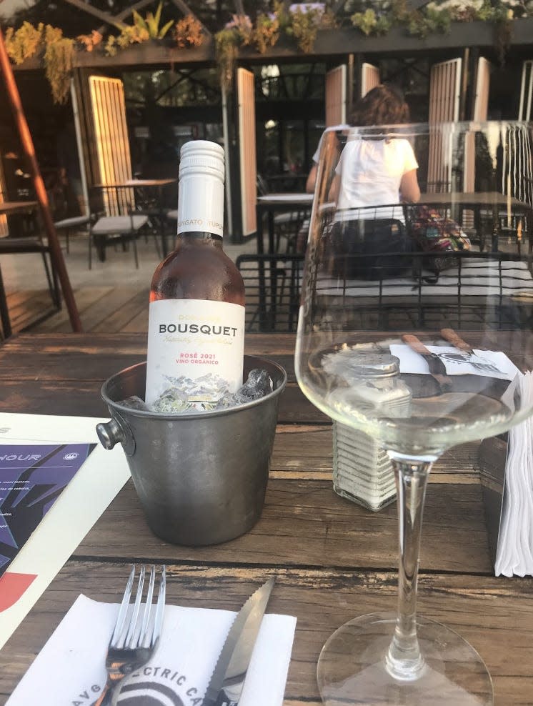 bottle of rose in an ice bucket on table with empty wineglass beside it