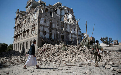 Houthi Shiite rebels walk amid the rubble of the Republican Palace that was destroyed by Saudi-led airstrikes, in Sanaa, Yemen - Credit: AP Photo/Hani Mohammed