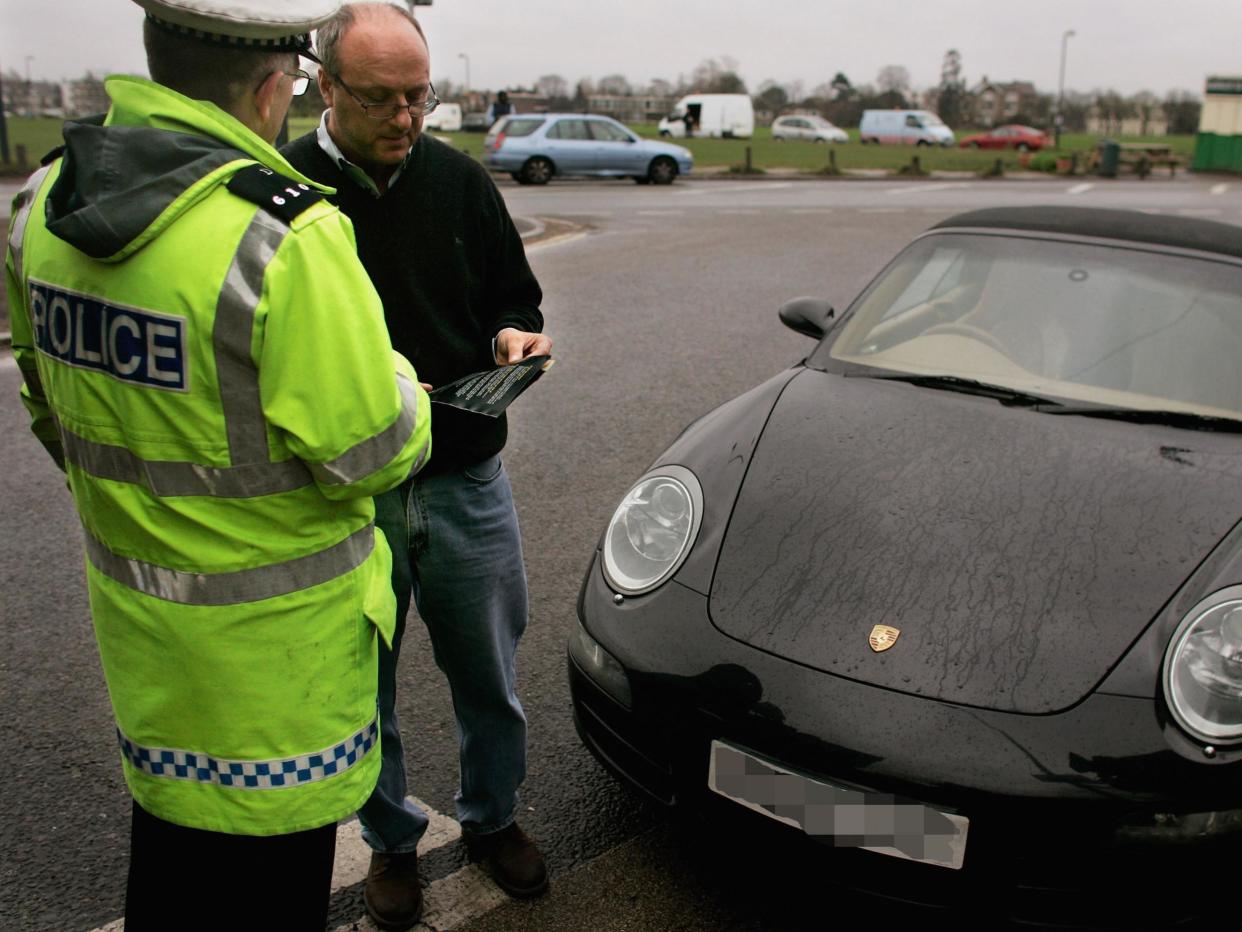 A Police officer hands a leaflet to a driver caught using his telephone whilst driving: Getty