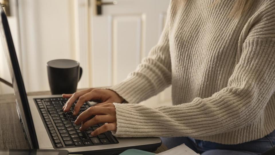 An unrecognisable young woman using her laptop and completing some work at home in Northumberland, North East England.