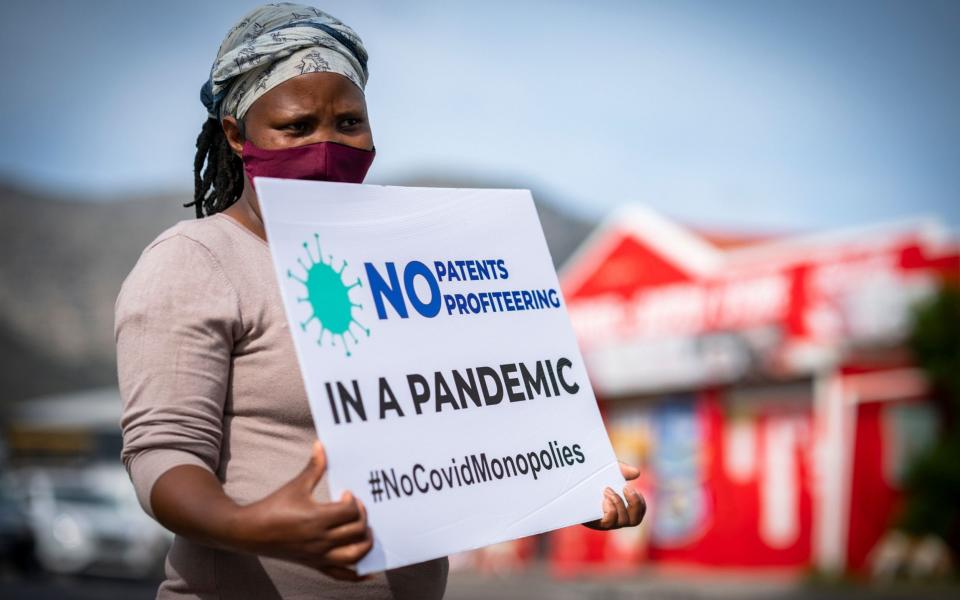 A member of the People's Vaccine Campaign of South Africa protests outside the Johnson & Johnson offices in Cape Town - Shutterstock