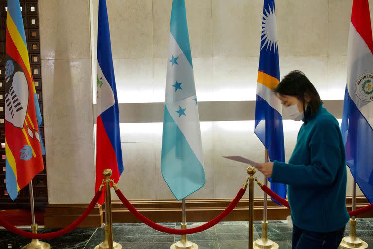 Una mujer camina junto a una bandera de Honduras en el Ministerio de Asuntos Exteriores de Taiwán en Taipei el 15 de marzo de 2023.